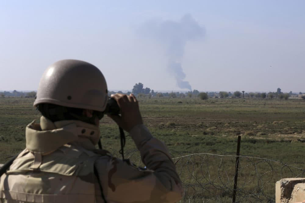An Iraqi soldier watches smoke rising after an airstrike by U.S.-led international coalition warplanes against ISIS, on the border between Syria and Iraq in Qaim, Anbar province, Iraq, Nov. 13, 2018. (Hadi Mizban/AP)
