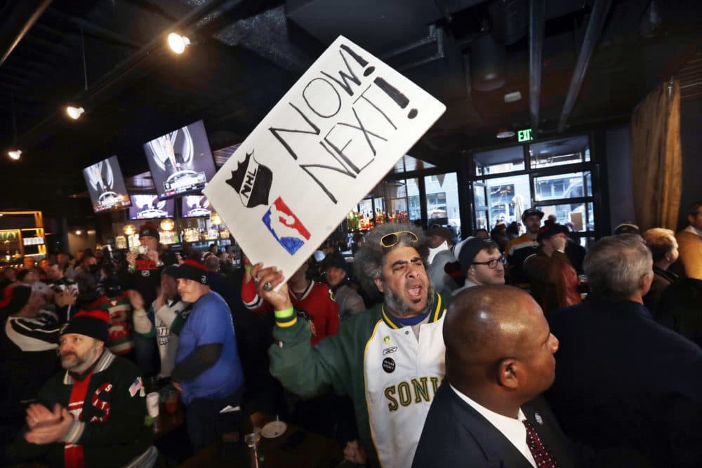 Kris &quot;Sonic Guy&quot; Brannon holds up a sign in support of adding an NBA team following the announcement of a new NHL hockey team in Seattle, at a celebratory party Tuesday, Dec. 4, 2018, in Seattle.  (AP Photo/Elaine Thompson)