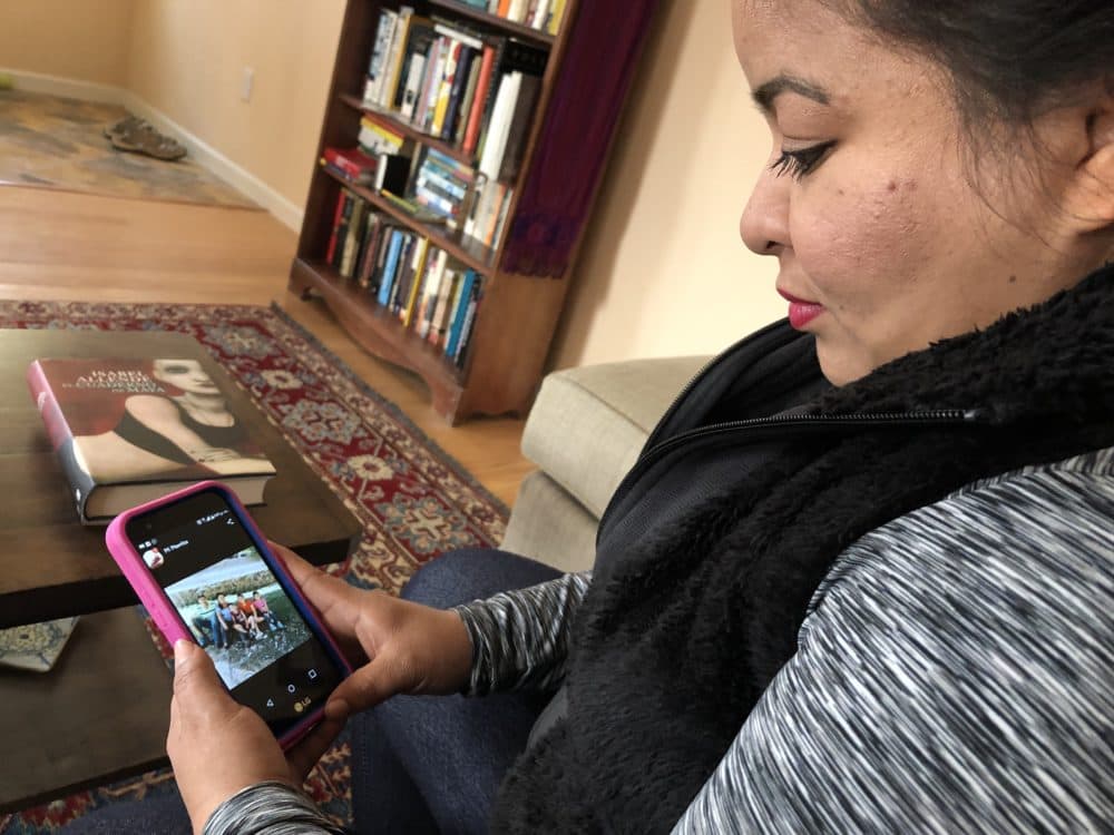 Veronica Aguilar looks at a photo of her family in El Salvador in the Moriartys' living room in Pinole on Nov. 18, 2018. Aguilar, an asylum applicant, traveled to the U.S. border in a caravan last year. (Farida Jhabvala Romero/KQED)