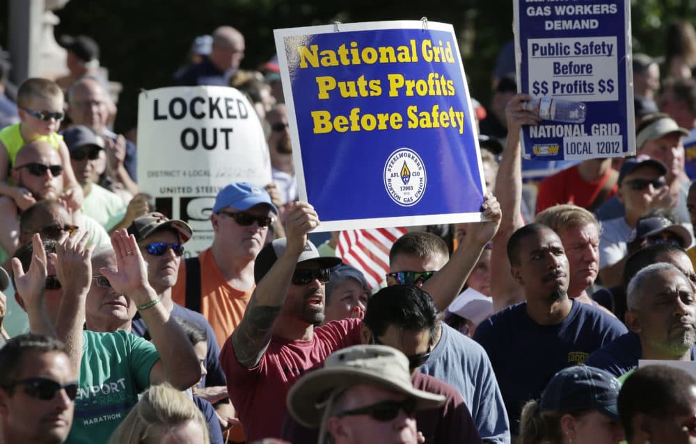 Protesters display placards during a rally July 18 in front of the State House, in Boston, held to call attention to the lockout of natural gas workers from their jobs by National Grid in dozens of communities across the state. (Steven Senne/AP)