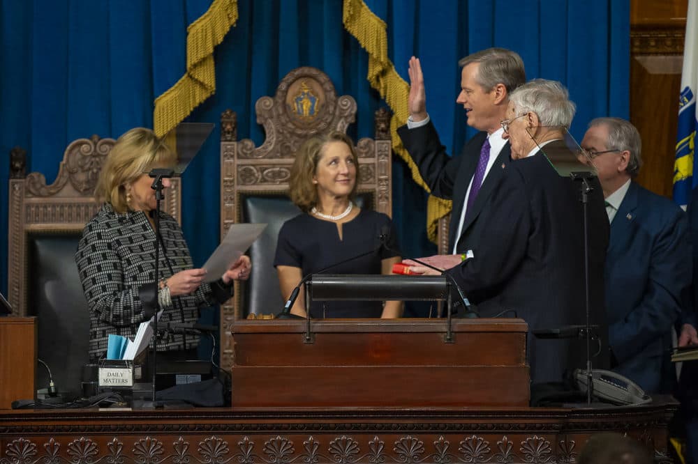 Baker is sworn in by Senate President Karen Spilka in the House Chamber as his wife Lauren, center, and his father, Charles D. Baker, watch. (Jesse Costa/WBUR)