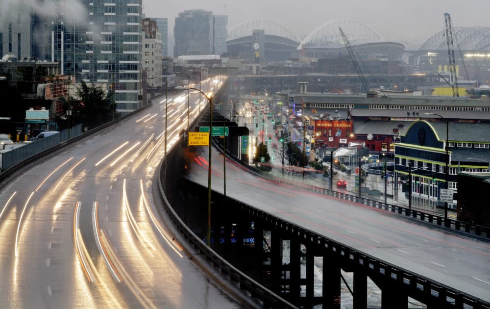 In this long-exposure photo taken Thursday, Jan. 3, 2019, headlights and taillights of Alaskan Way Viaduct traffic lines the highway ahead of an upcoming closure of the roadway, as the city's sports stadiums are seen in the distance, in Seattle. The double-decker highway along Seattle's waterfront was shut down for good Friday, Jan. 11, ushering in what officials say will be one of the most painful traffic periods in the city's history. (Elaine Thompson/AP)