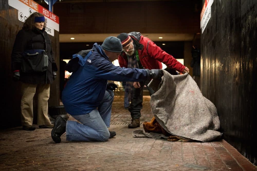 From the city's 2013 homeless census, Jim Greene, the director of emergency shelters for the Boston Public Health Commission (in red), and another volunteer lift a blanket off of a homeless woman at Downtown Crossing to check if she is OK. (Jesse Costa/WBUR)