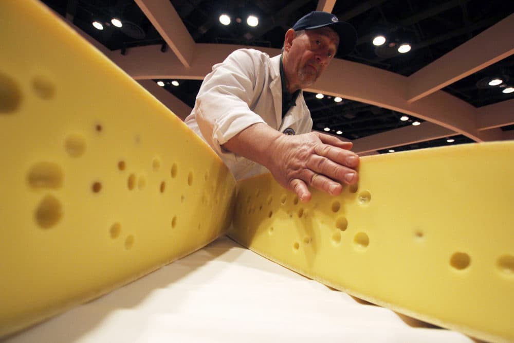 Americans are eating more cheese now than ever before: The country consumed around 37 pounds per capita in 2017. But it's not enough to make a dent in the U.S.' 1.4 billion-pound cheese surplus. Pictured: A volunteer opens a round of Swiss cheese during the World Championship Cheese Contest, March 6, 2018, in Madison, Wis. (Carrie Antlfinger/AP)