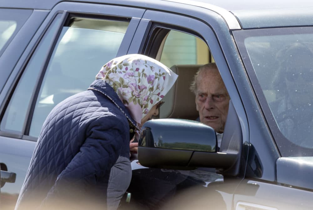 Britain's Prince Philip sits in the driving seat of a car, talking to Queen Elizabeth II during the Royal Windsor Horse Show in Windsor, England, Friday May 11, 2018. (Steve Parsons/PA via AP)