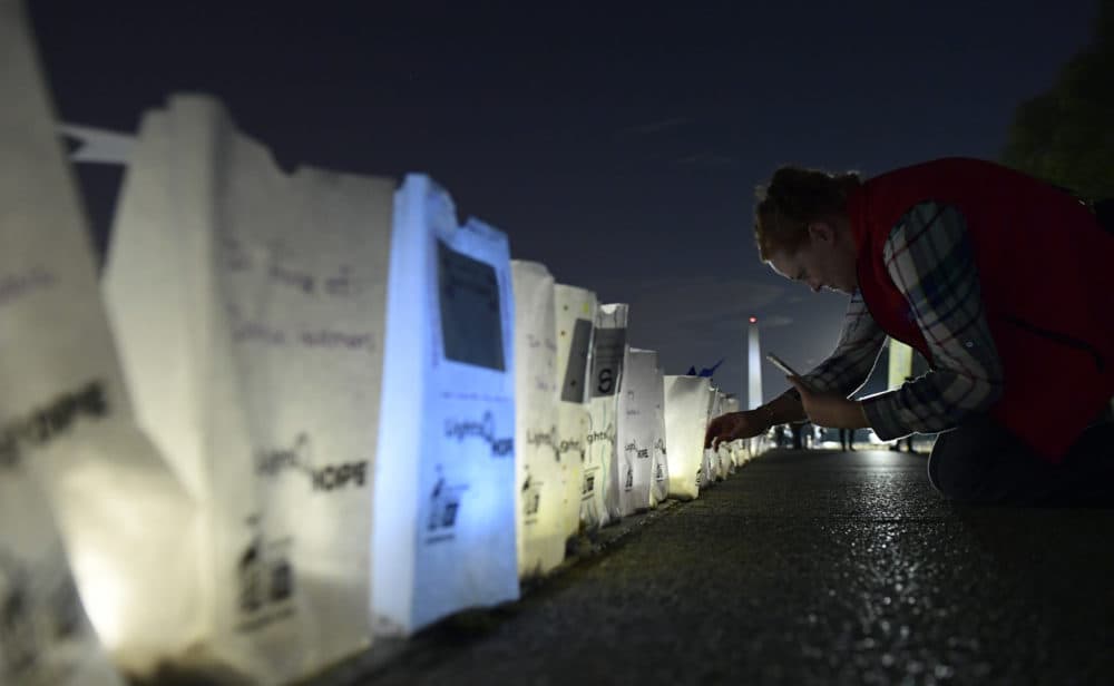 Dawn Scott of Cody, Wyo., a 20-year cancer survivor, photographs lighted bags in memory of friends and family who died of cancer during a &quot;Lights of HOPE&quot; ceremony in Washington, Tuesday, Sept. 25, 2018. (Susan Walsh/AP)