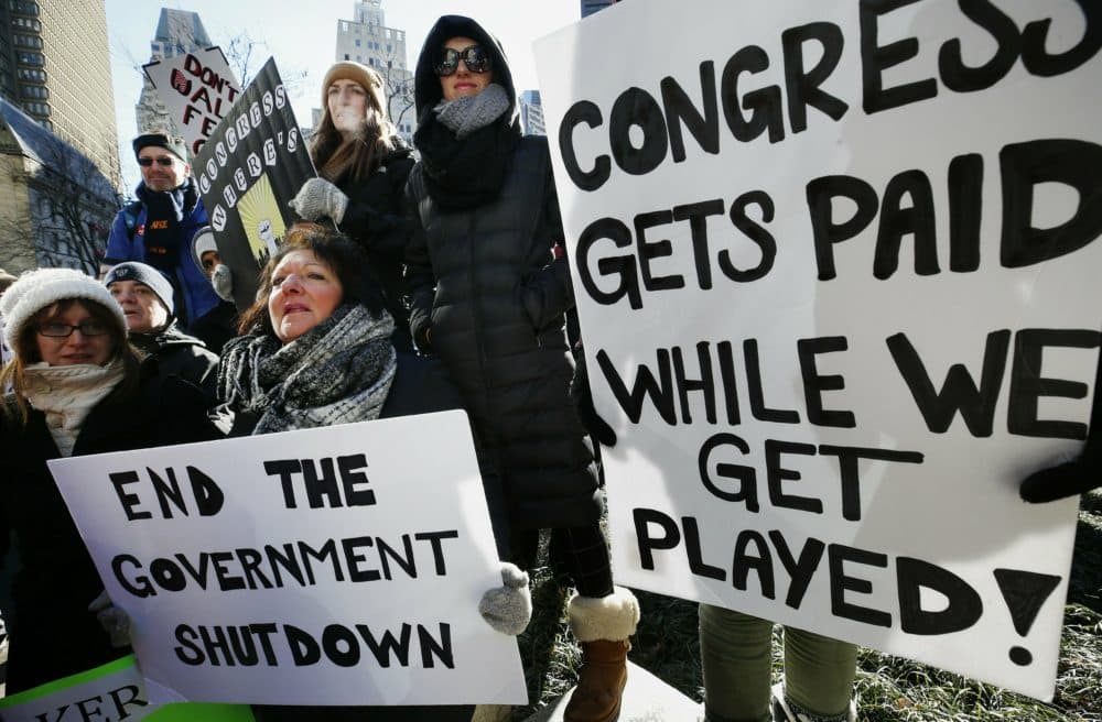 Government workers and their supporters hold signs during a protest in Boston Friday. The workers rallied with Democratic U.S. Sen. Ed Markey and other supporters to urge that the Republican president put an end to the shutdown so they can get back to work. (Michael Dwyer/AP)