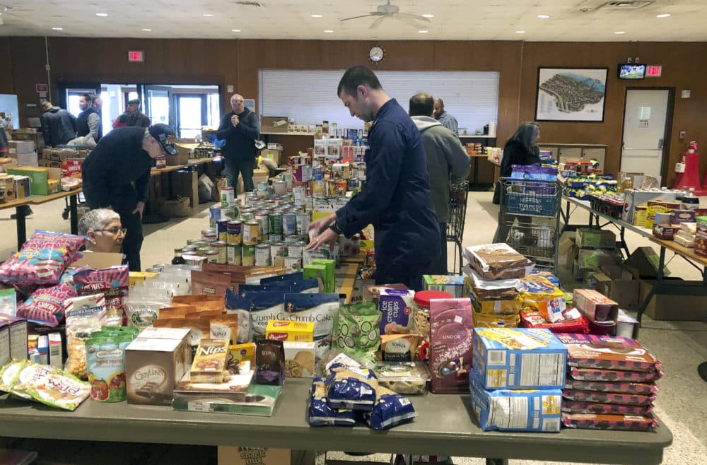 In this Thursday, Jan. 17, 2019 photo, a member of the U.S. Coast Guard arranges donated canned goods at a pop-up food pantry at the U.S. Coast Guard Academy in New London, Conn., that was set up by several Coast Guard-related advocacy groups. (Susan Haigh/AP)
