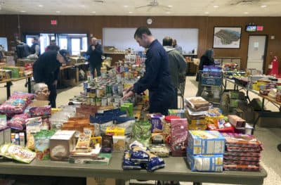 In this Thursday, Jan. 17, 2019 photo, a member of the U.S. Coast Guard arranges donated canned goods at a pop-up food pantry at the U.S. Coast Guard Academy in New London, Conn., that was set up by several Coast Guard-related advocacy groups. (Susan Haigh/AP)
