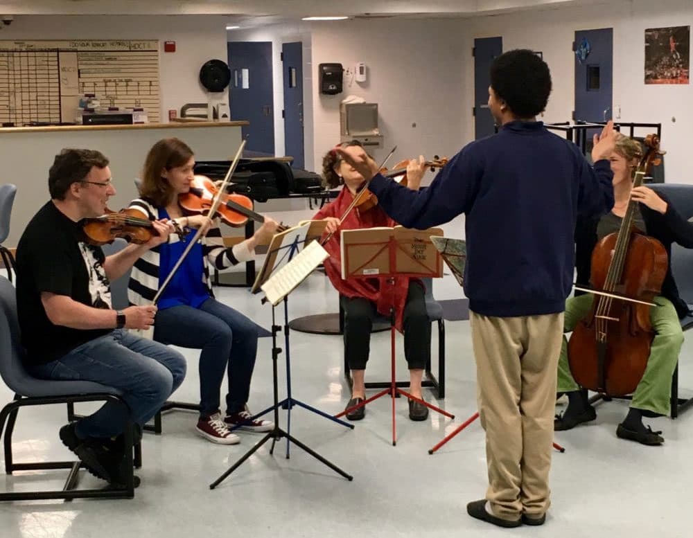 A teen at a Youth Services center tries to conduct musicians from the Sarasa Chamber Music Ensemble. (Courtesy Bruce Mendelsohn)