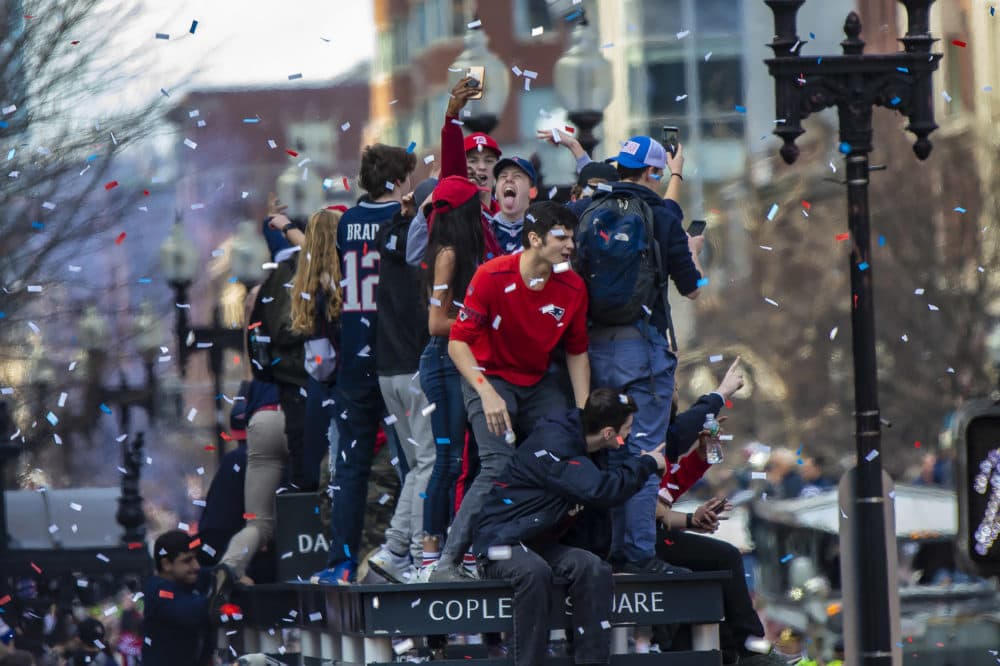 Patriots fans climbed up onto a bus shelter on Boylston St. to get a better position to see the parade. They were promptly told by police to get down. (Jesse Costa/WBUR)