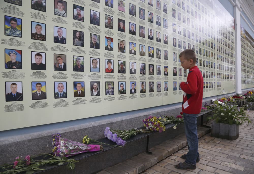 A boy stands as he looks at a photo of his father at memorial wall with photos of servicemen killed in the conflict with pro-Russian separatists in the country's east, in Kiev, Ukraine in 2017. (Efrem Lukatsky/AP)