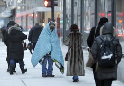 A homeless man who did not give his name bundles up in blankets in downtown Chicago during a deep freeze. (Kiichiro Sato/AP)