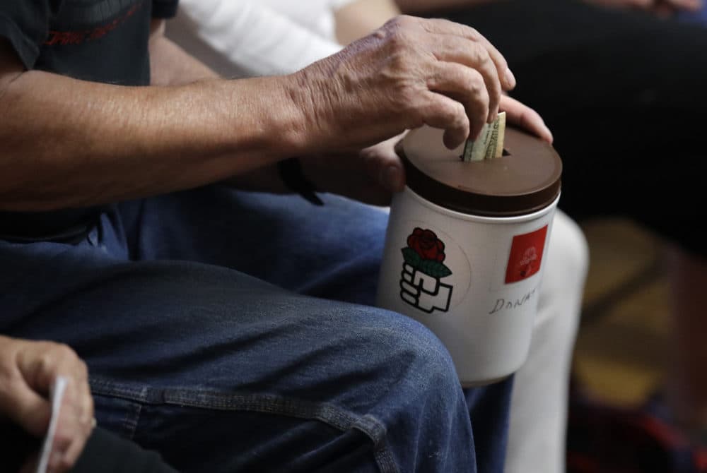 A patron puts a bill in a donation bucket, which features a red rose symbol, during a meeting of members of the Southern Maine Democratic Socialists of America in Portland, Maine, Monday, July 16, 2018. (Charles Krupa/AP)