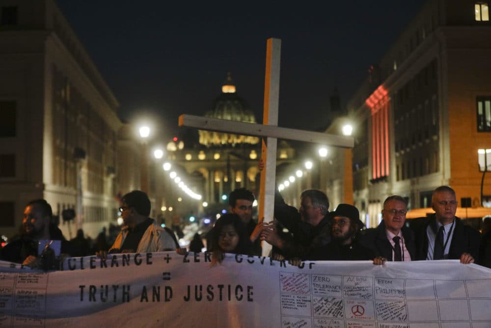 Survivors of sex abuse hold a cross as they gather in front of Via della Conciliazione, the road leading to St. Peter's Square, during a twilight vigil prayer of the victims of sex abuse, in Rome, Thursday, Feb. 21, 2019. (Gregorio Borgia/AP)