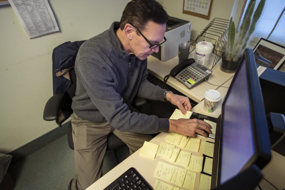 Army veteran Chris Riga rearranges Post-it Notes on his desk, which he uses to assist him in remembering tasks he has to do throughout the day at his job as patient experience coordinator at the VA in Northampton, Mass. (Jesse Costa/WBUR)