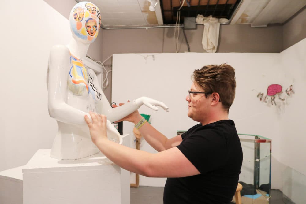 Kal Anderson adjusts a statue at Dorchester Art Project. (Olivia Deng for WBUR)