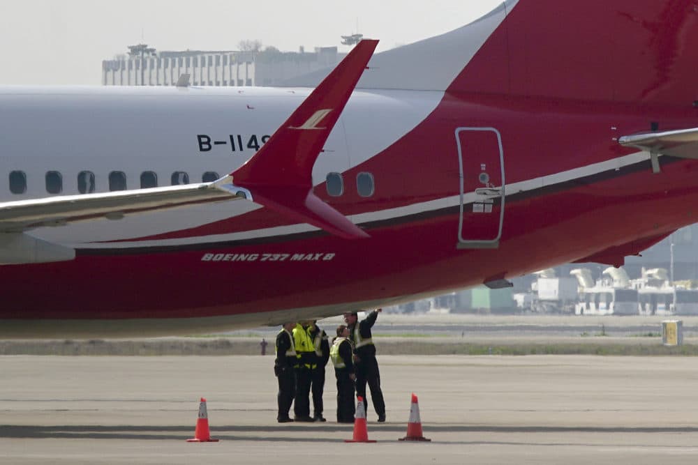 Ground crew chat near a Boeing 737 MAX 8 plane operated by Shanghai Airlines parked on tarmac at Hongqiao airport in Shanghai, China on Tuesday. (AP)