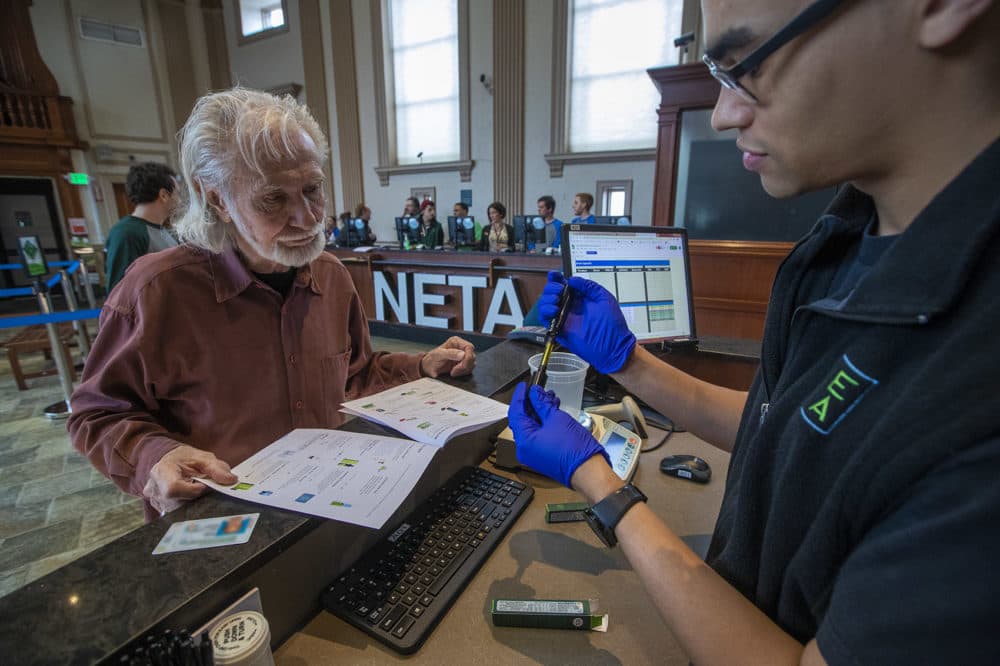 NETA associate Kyle Chambers examines a vaporizor cartridge and shows it to patient Richard Morse for his approval at the NETA marijuana dispensary in Brookline. (Jesse Costa/WBUR)