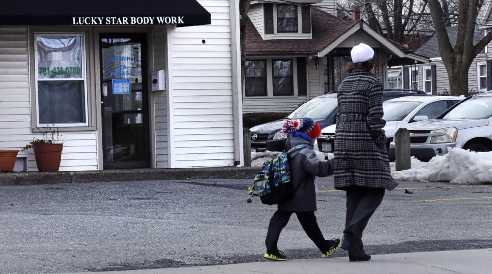 A woman and child walk past the Lucky Star Body Work massage spa in Stoneham, Mass., Monday, Feb. 25, 2019. The massage spa was shut down twice in 2018 for human sex trafficking. (Charles Krupa/AP)