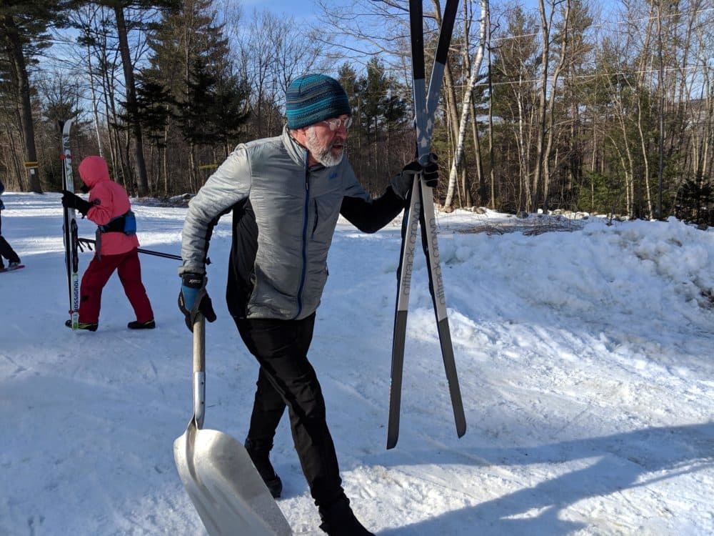 Windblown ski area owner Al Jenks spent a sunny Friday in late February skiing around his property, using a shovel to cover up persistent bare patches of ground with fresh snow. (Annie Ropeik/NHPR)