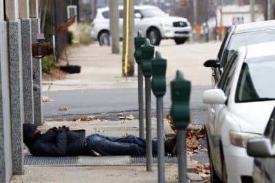 A man who is homeless takes advantage of the warm air coming from a sidewalk vent to stay warm in downtown Jackson, Miss., Wednesday, Dec. 27, 2017. (Rogelio V. Solis/AP)