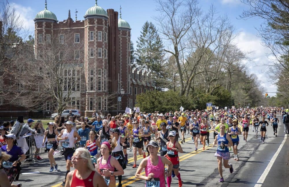 As the sun comes out towards the middle of the day, marathon runners race through the “scream tunnel” at Wellesley. (Robin Lubock/WBUR)