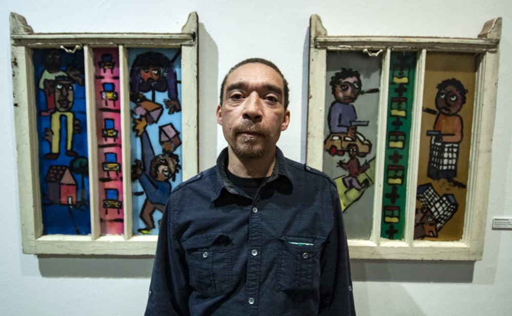 Chicago artist Robert Johnson stands in front of two of his window paintings at Intuit: The Center for Intuitive and Outsider Art in Chicago. (Chris Bentley/Here & Now)