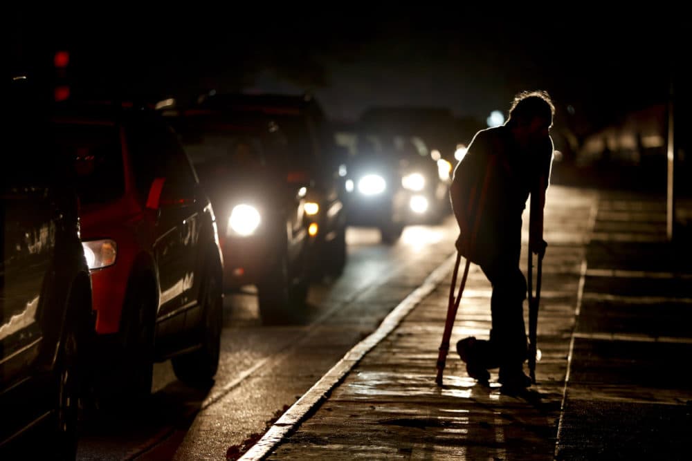 A man on crutches is illuminated by headlights of oncoming traffic, in Caracas, Venezuela during a blackout on March 29. Venezuelans are struggling to understand the Sunday, March 31, 2019 announcement that the nation’s electricity is being rationed to combat daily blackouts. (Natacha Pisarenko/AP)