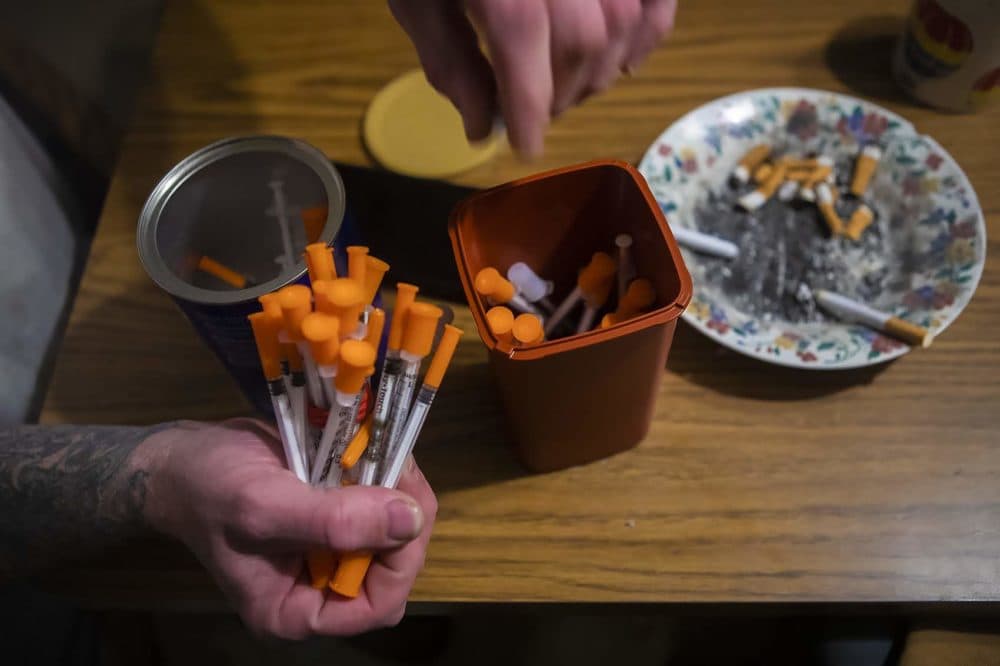 A drug user in Lewiston, Maine, disposes used needles into a one quart-sized sharps container to be exchanged for brand new supply of needles. (Jesse Costa/WBUR)