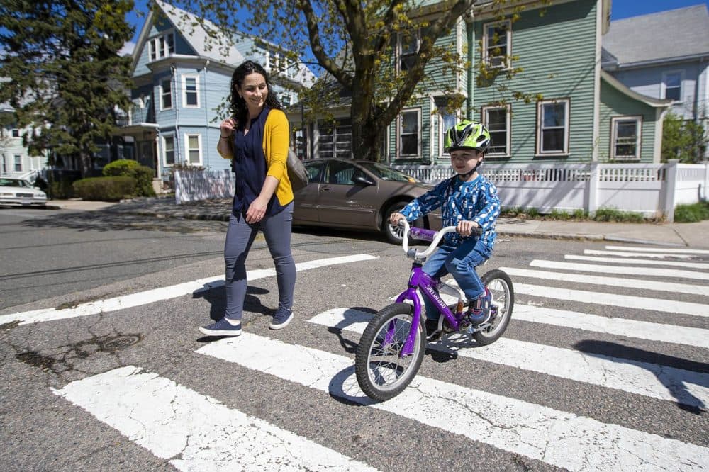 Elizabeth Pinsky walks alongside her son, Ben, while he rides his bicycle home in Somerville. (Jesse Costa/WBUR)