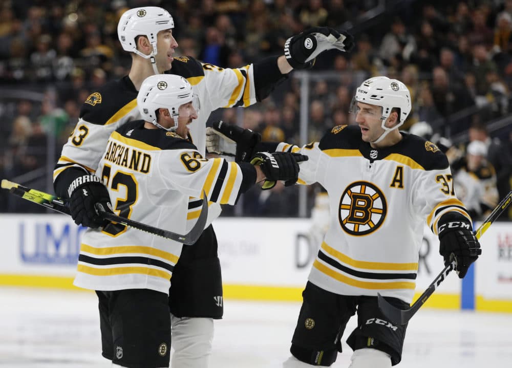 Boston Bruins left wing Brad Marchand (63) celebrates with teammates Zdeno Chara, back left, and Patrice Bergeron after scoring during a game this season. (John Locher/AP)