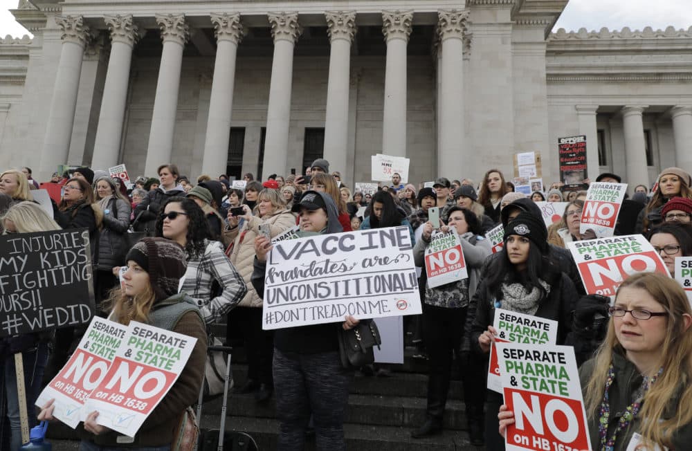 In this Feb. 8, 2019 photo, people hold signs at a rally held in opposition to a proposed bill that would remove parents' ability to claim a philosophical exemption to opt their school-age children out of the combined measles, mumps and rubella vaccine at the Capitol in Olympia, Wash. (AP Photo/Ted S. Warren)