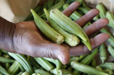 A customer checks the firmness of fresh okra at Doris Berry Produce stand in Jackson, Miss. (Rogelio V. Solis/AP)