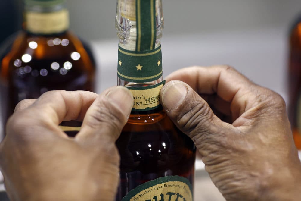 A distillery worker affixes a label to a bottle of Michter's Kentucky Straight Bourbon at the Michter's Shively Distillery in Louisville, Ky. (Luke Sharrett for Here &amp; Now)
