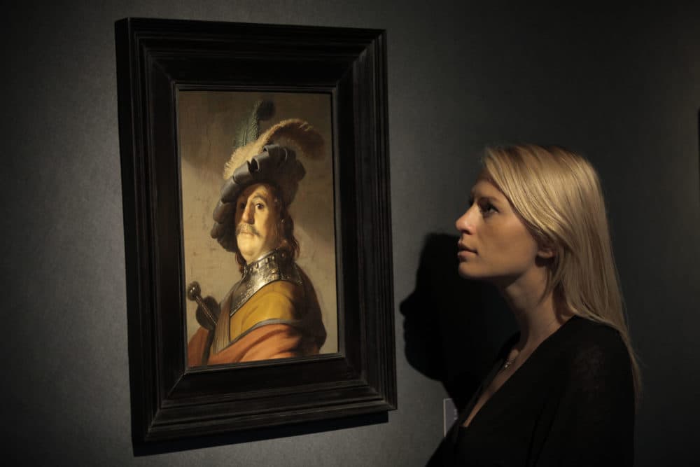 An auction house worker poses in front of a Rembrandt masterpiece entitled &quot;A Bust of a Man in a Gorget and Cap&quot; that was sold at auction for 8.4 million pounds in London 2012. (Lefteris Pitarakis/AP)