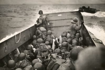 Tightly packed troops crouch inside their LCVP as it plows through a wave. In the distance is the coast of Normandy. (Courtesy of The National WWII Museum)