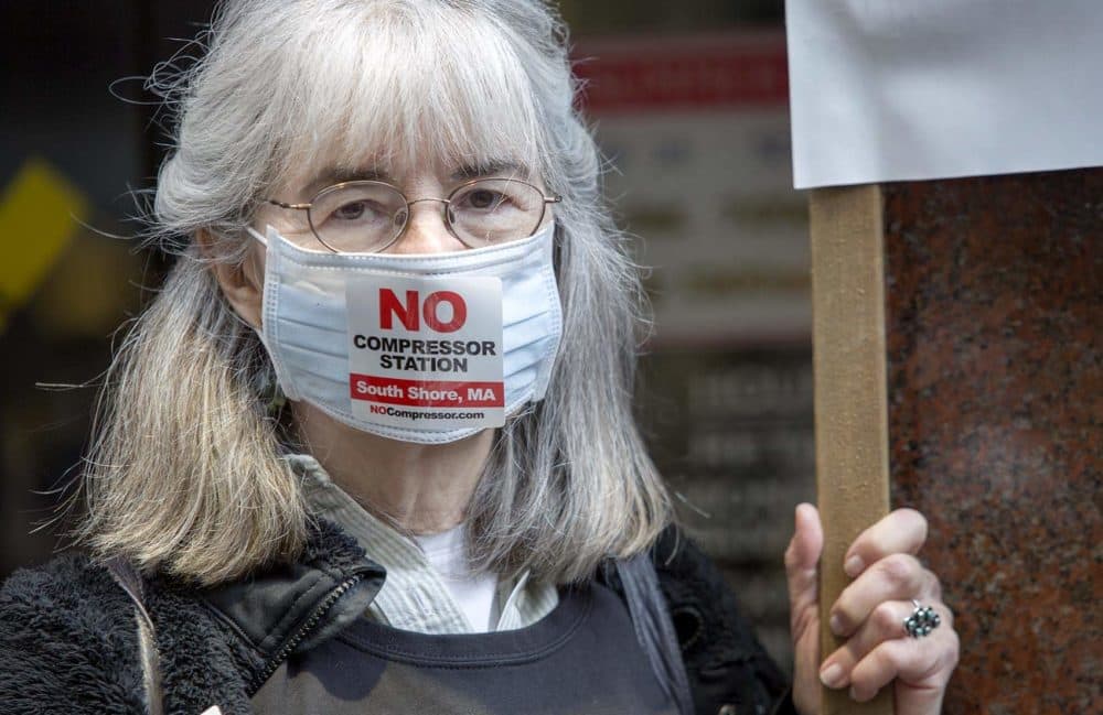 Barbara Baatz wears a face mask and &quot;No Compressor Station&quot; sticker at a May protest against the development of the Weymouth compressor station. (Robin Lubbock/WBUR)