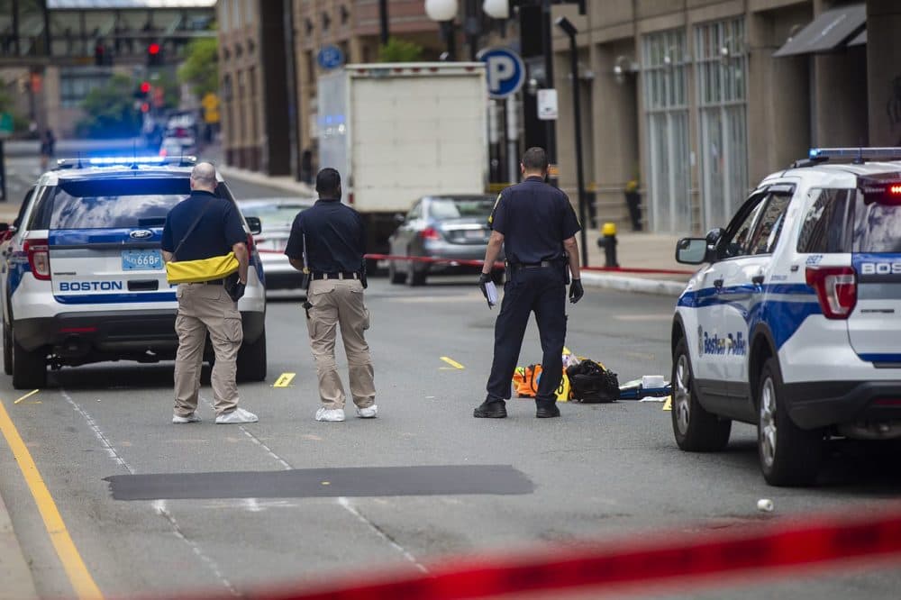 Boston police examine evidence on the ground in front of the Colonnade Hotel on Huntington Avenue following a shooting that claimed one life. (Jesse Costa/WBUR)