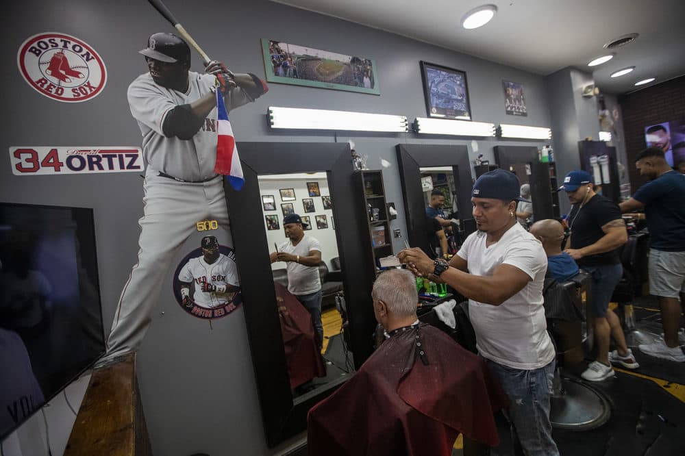 With the walls adorned with images of Big Papi, Gino Almonte gives a haircut to a patron at MLB Barbers on Tremont Street, where David Ortiz gets his hair cut regularly. (Jesse Costa/WBUR)