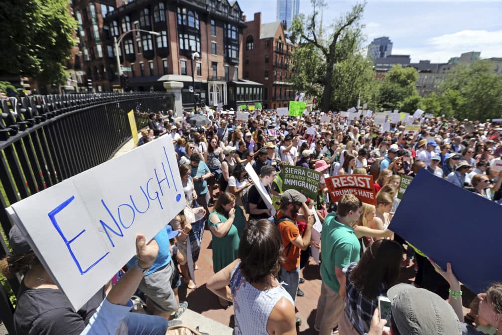 People rally outside the State House in Boston on June 20, 2018, to protest how immigrants are being treated both on the border with Mexico and in Massachusetts. (Elise Amendola/AP)