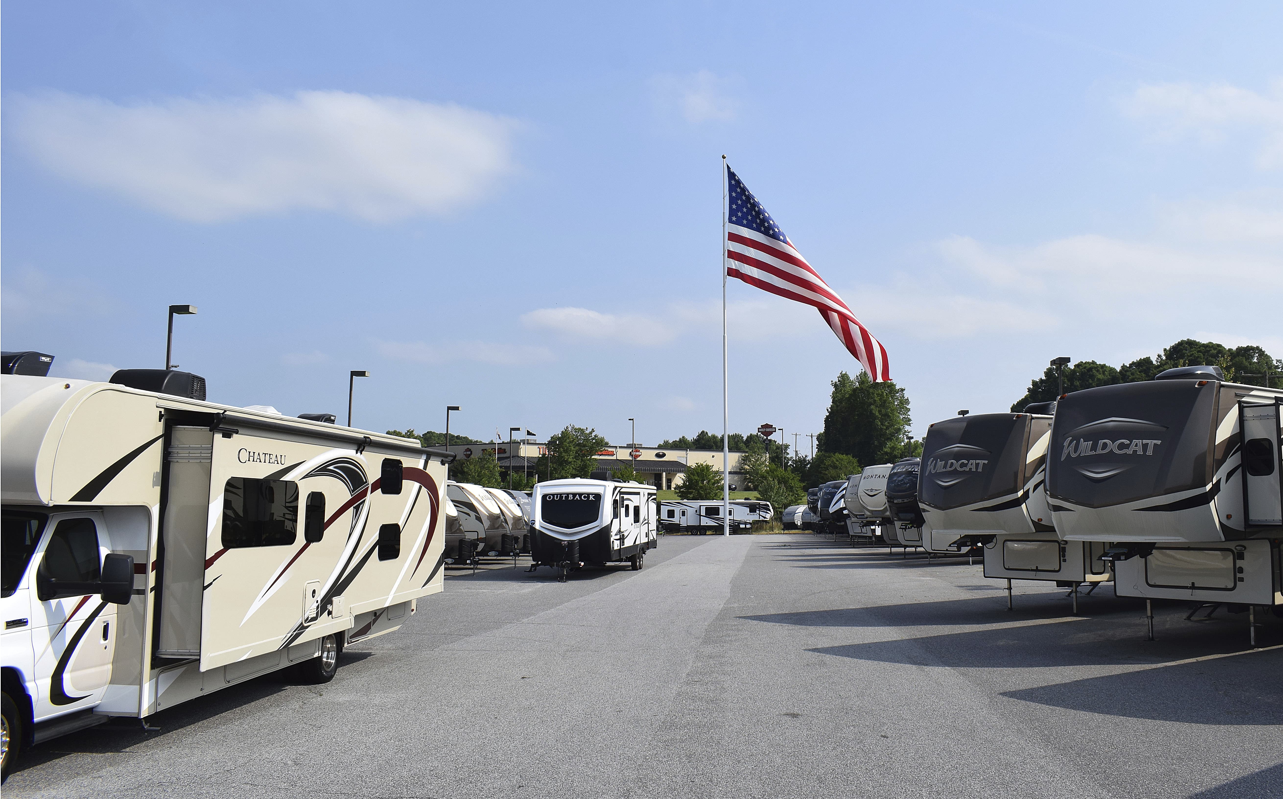 A giant American flag that's been at the center of a local controversy blows in the wind at Gander RV, in Statesville, N.C. The North Carolina city has voted against the flying of really big flags, holding its ground against reality TV star Marcus Lemonis' huge Stars and Stripes. (Jennifer Munday/Camping World via AP)