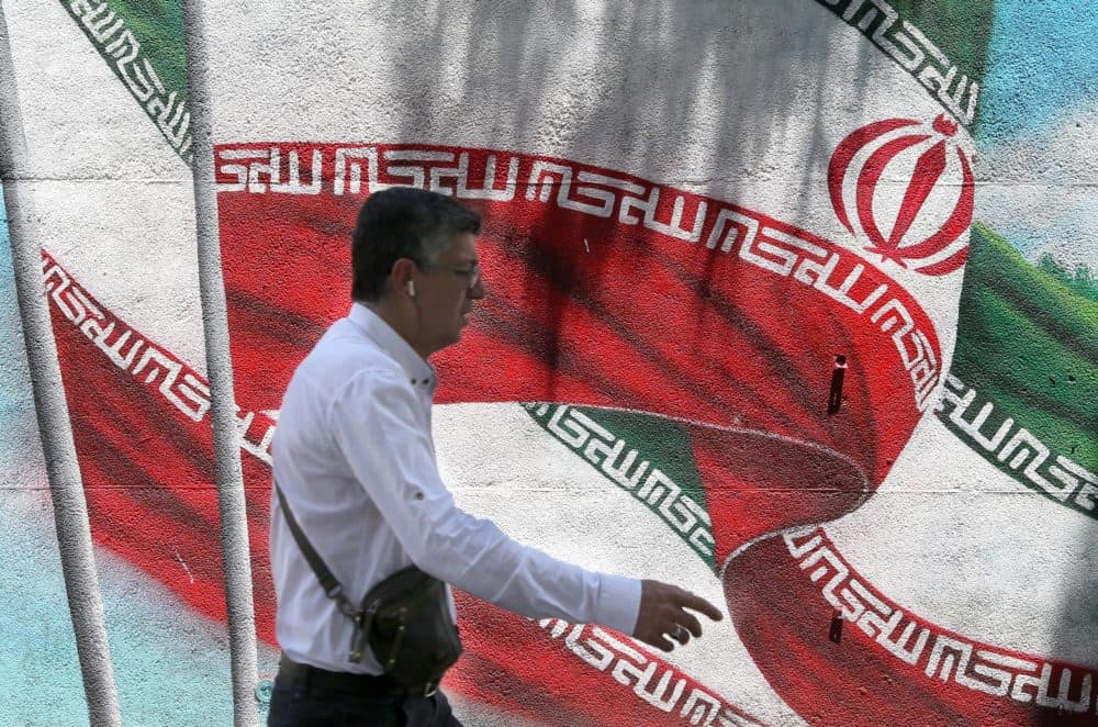 An Iranian man walks past a mural painted with the Iranian flag in Tehran. (Atta Kenare/AFP/Getty Images)