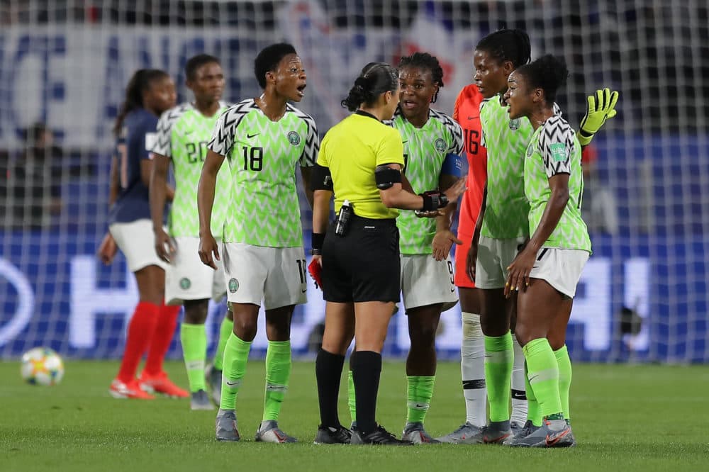 Nigeria players confront a referee after she awards France a penalty following a VAR review. (Richard Heathcote/Getty Images)