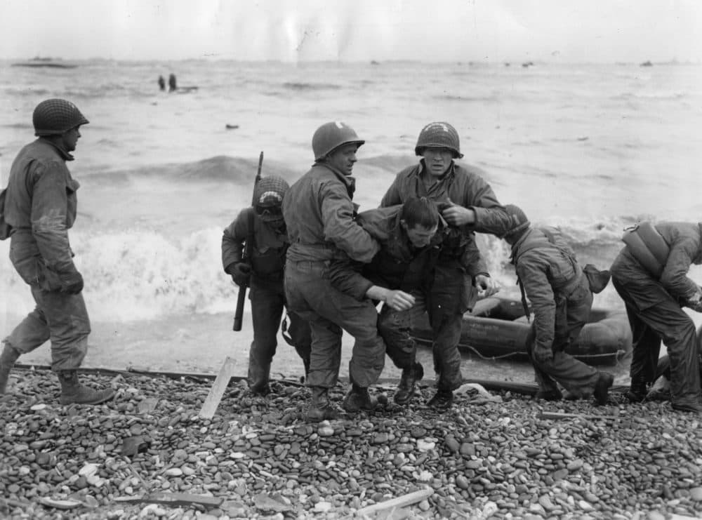 American troops helping their injured friends from a dinghy after the landing ship they were on was hit by enemy fire during the Allied invasion of France on D-Day. (Fox Photos/Getty Images)
