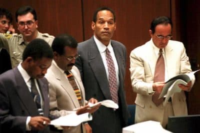 O.J. Simpson watches as the jury in his double-murder trial enters the courtroom, Feb. 2, 1995, in Los Angeles, Calif. His attorneys (left to right) Carl Douglas, Johnnie Cochran Jr. and Robert Shapiro look over documents. (Pool/AFP/Getty Images)