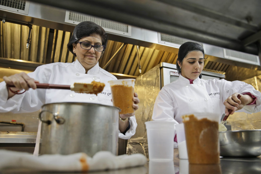 Rachana Rimel, left, and Dhuha Jasim package Adas, a lentil dish from Eritrea, in New York. Employees at Eat Offbeat are either refugees or asylum-seekers who fled their home countries. They're cooking foods from those places, including Iraq and Nepal. (Seth Wenig/AP)