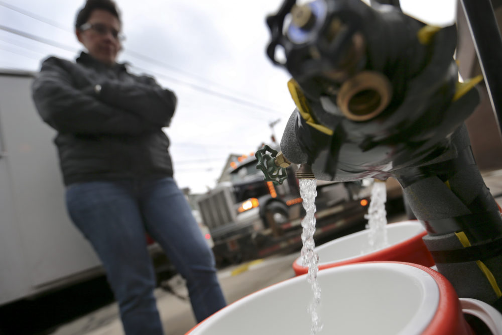 In this 2017 file photo, Ronette Cooley watches as she fills containers with water at a city fire station in the Lawrenceville section of Pittsburgh on Wednesday, Feb. 1, 2017. (Keith Srakocic/AP)
