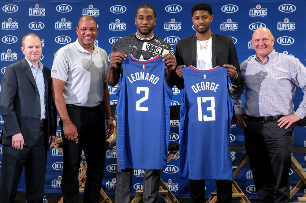 Kawhi Leonard, center, and Paul George, second from the right, holding their new team jerseys, pose with Los Angeles Clippers President of Basketball Operations Lawrence Frank, left, head coach Doc Rivers, second from the left, and team chairman Steve Ballmer during a press conference in Los Angeles, Wednesday, July 24, 2019. (Ringo H.W. Chiu/AP)