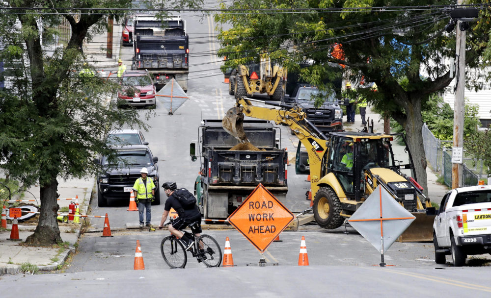 A bicyclist takes a turn at a road block as utility contractors dig up the road above natural gas lines along Brookfield Street in Lawrence, Mass. in September 2018. (Charles Krupa/AP)